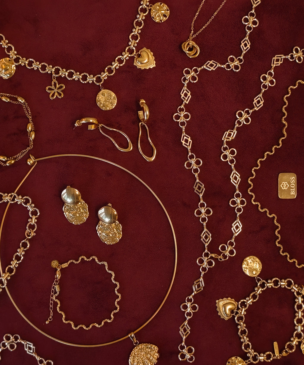Gouden BLOSS Essentials met Solene en Ovelle oorbellen en Odine sieraden op bordeauxrode stof