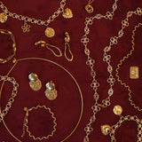 Gouden BLOSS Essentials met Solene en Ovelle oorbellen en Odine sieraden op bordeauxrode stof