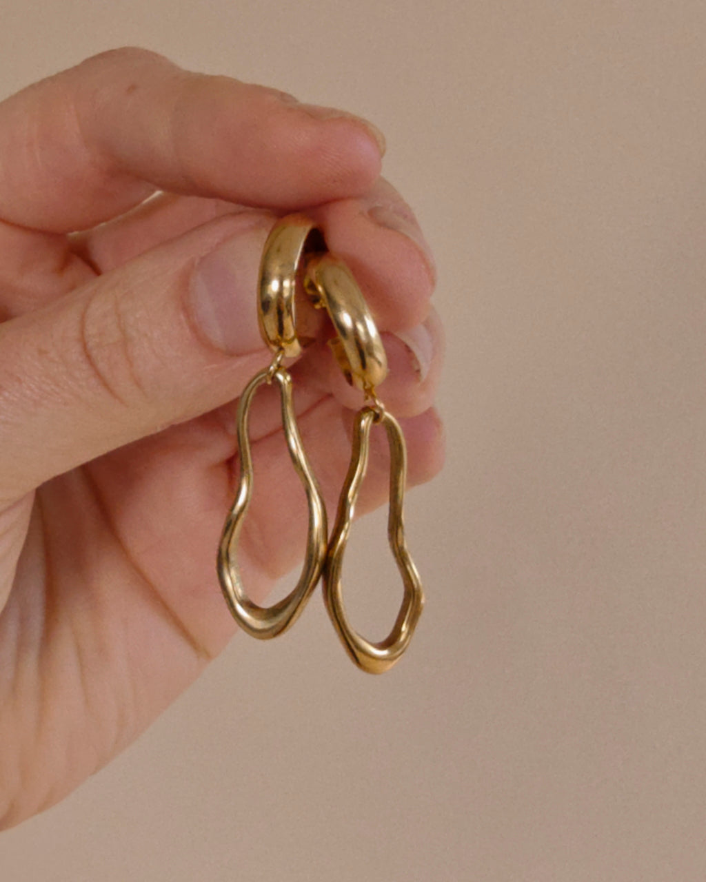 Ovelle gouden oorbellen in de hand voor een indruk van de grootte