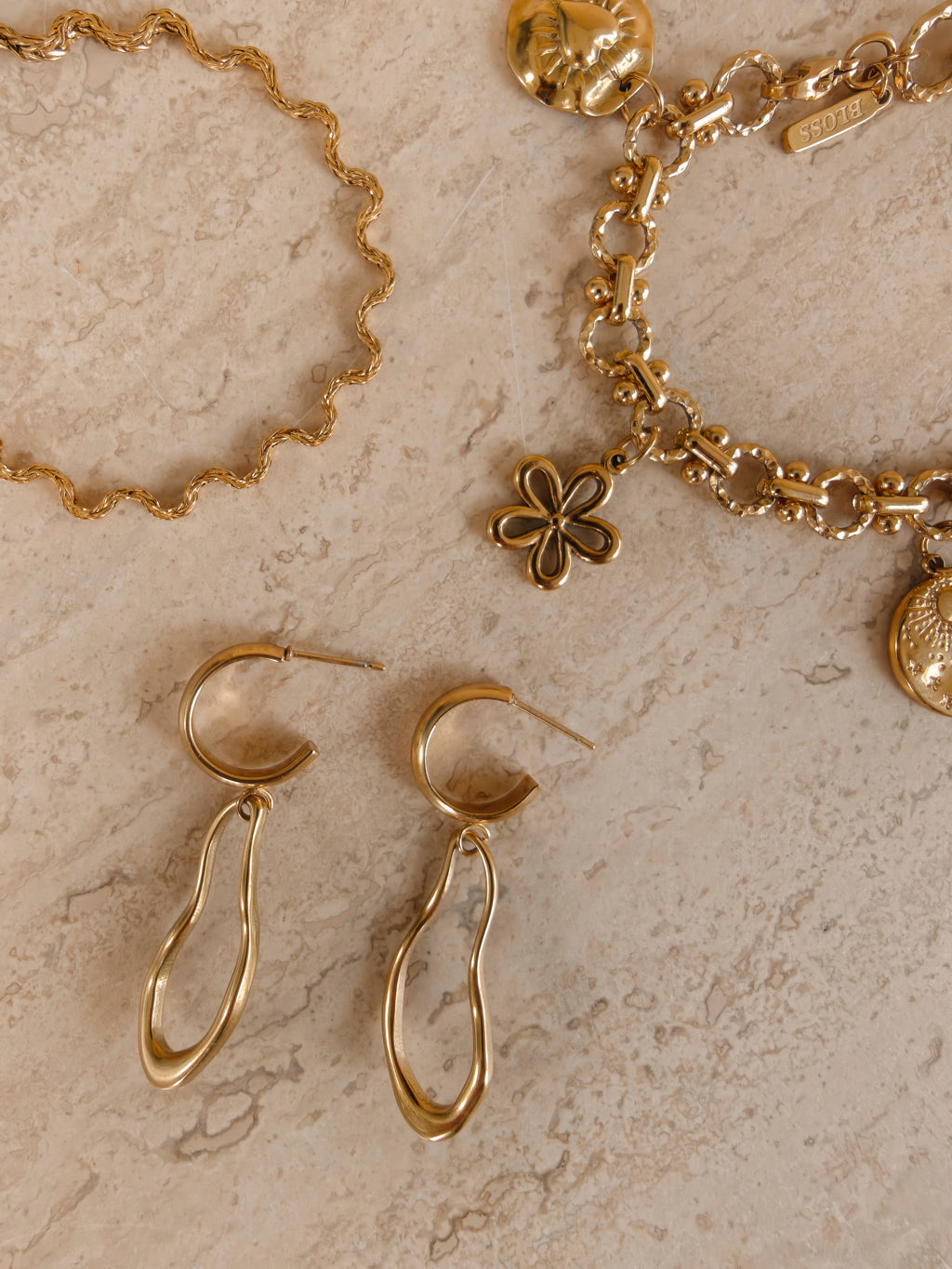 Ovelle oorbellen naast gouden Coquette en Odine sieraden