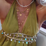 Gouden Coquette bedelketting en lange Fleurette Y-ketting gecombineerd met parels bij een groene outfit | gedragen