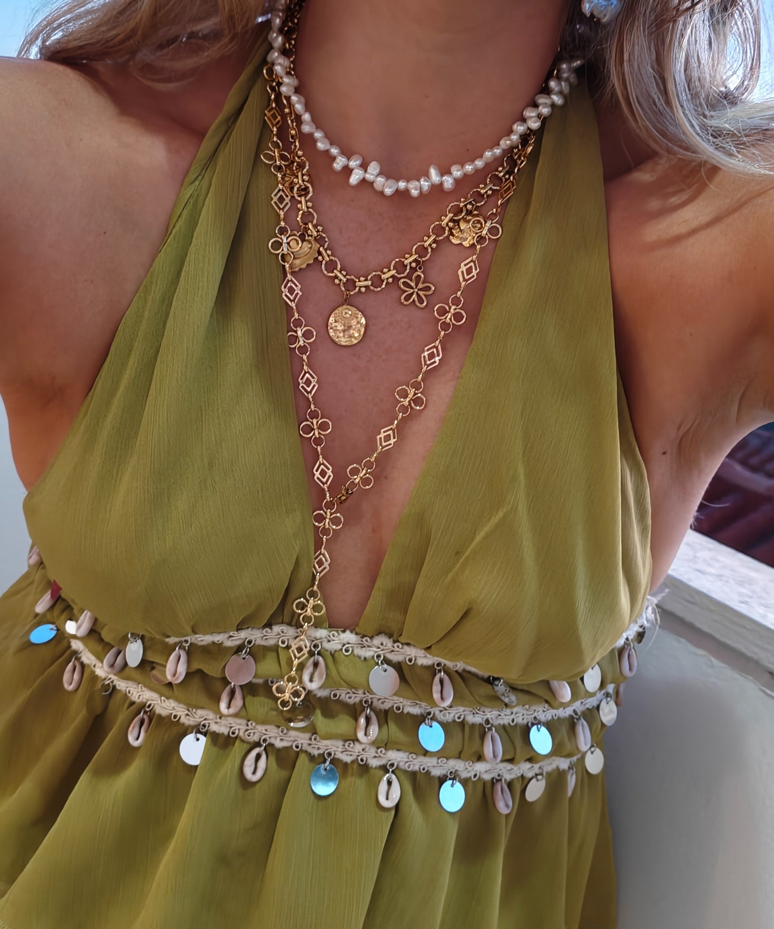 Gouden Coquette bedelketting en lange Fleurette Y-ketting gecombineerd met parels bij een groene outfit | gedragen