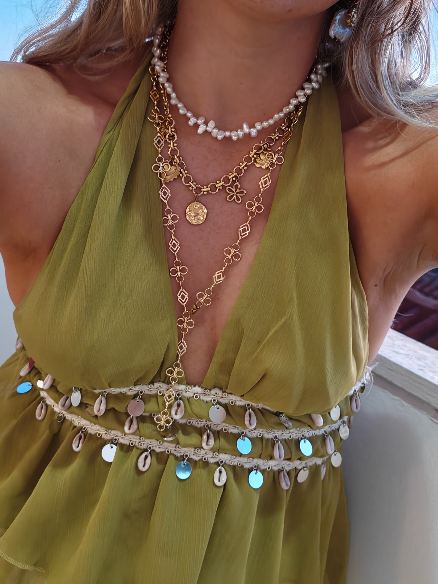 Gouden Coquette bedelketting en lange Fleurette Y-ketting gecombineerd met parels bij een groene outfit | gedragen
